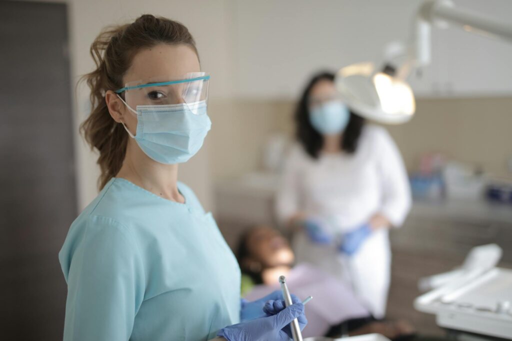 young female dentist in medical uniform with instruments standing in clinic