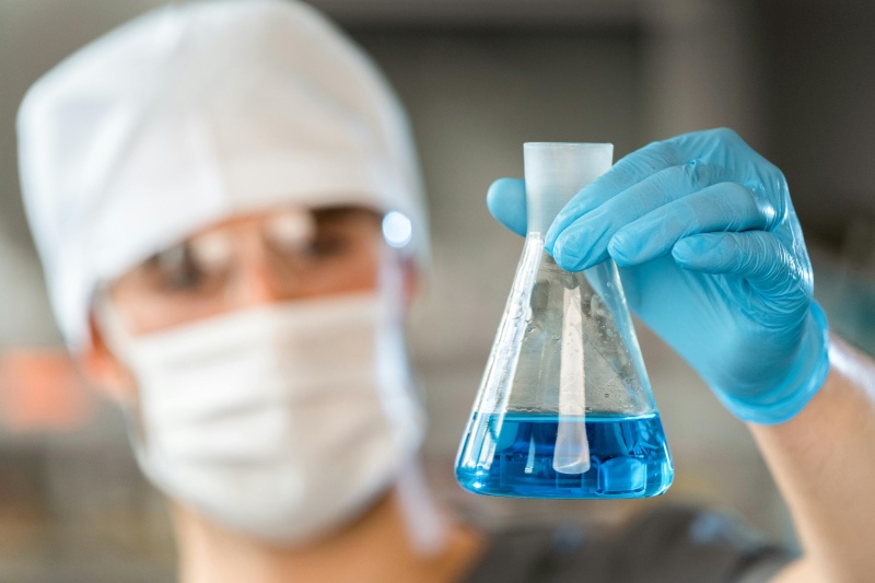 Scientist performing a chemistry experiment with a glass beaker in a lab setting