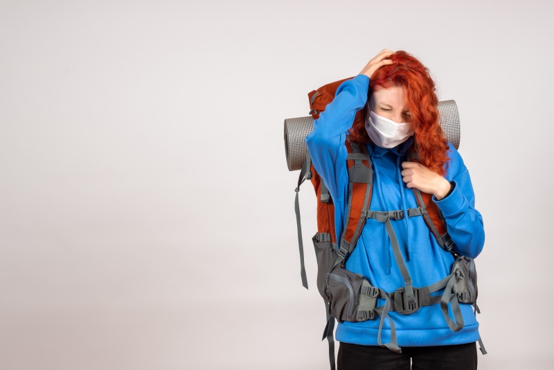 “Female trekker experiencing altitude sickness symptoms like headache and fatigue while hiking with backpack at high altitude”