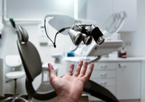 dental clinic scene dentist screening young swimmer gums pre-season, periodontal probe in mouth, healthy pink gums vs red inflamed gums, 70% systemic inflammation text, swimming goggles and trophies in background, shoulder pain prevention